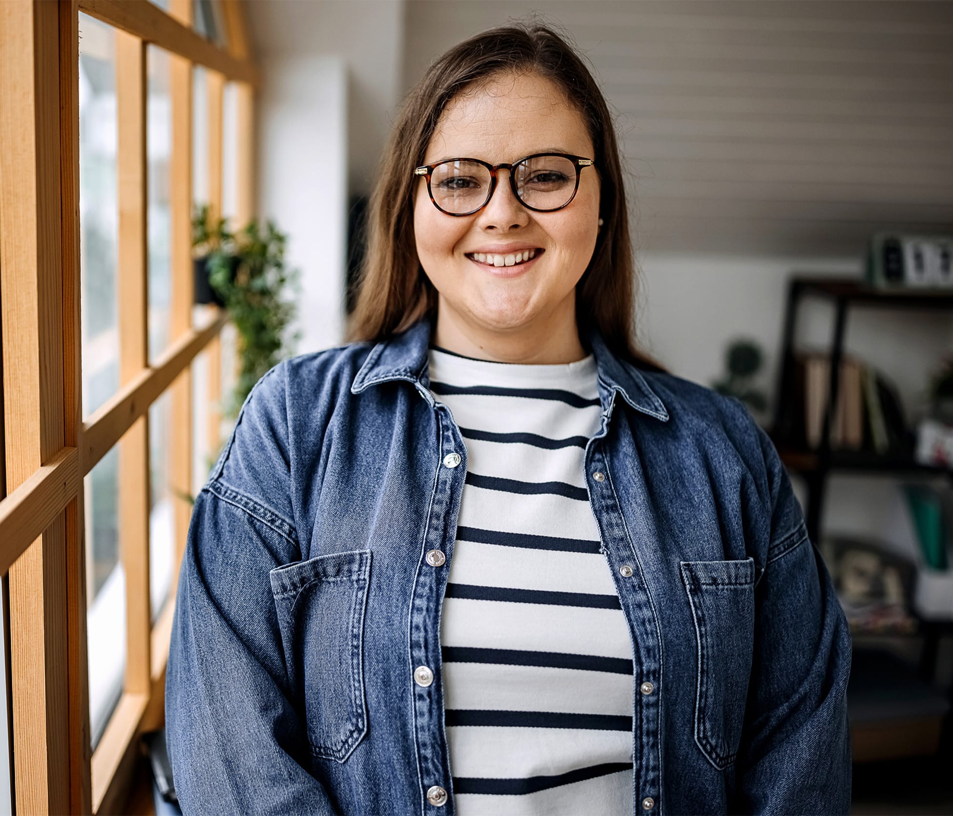 woman smiling and standing next to window