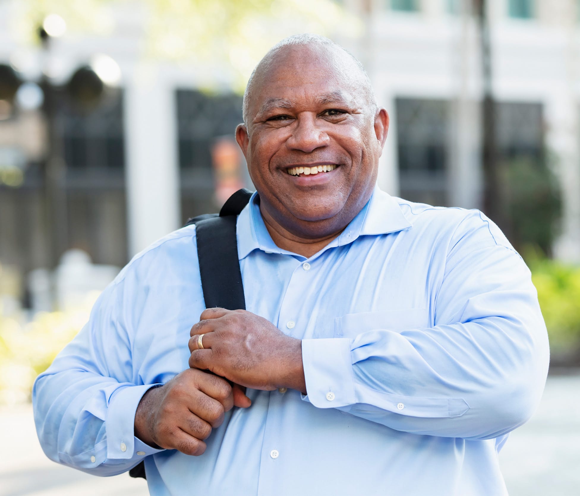 Man smiling and holding backpack