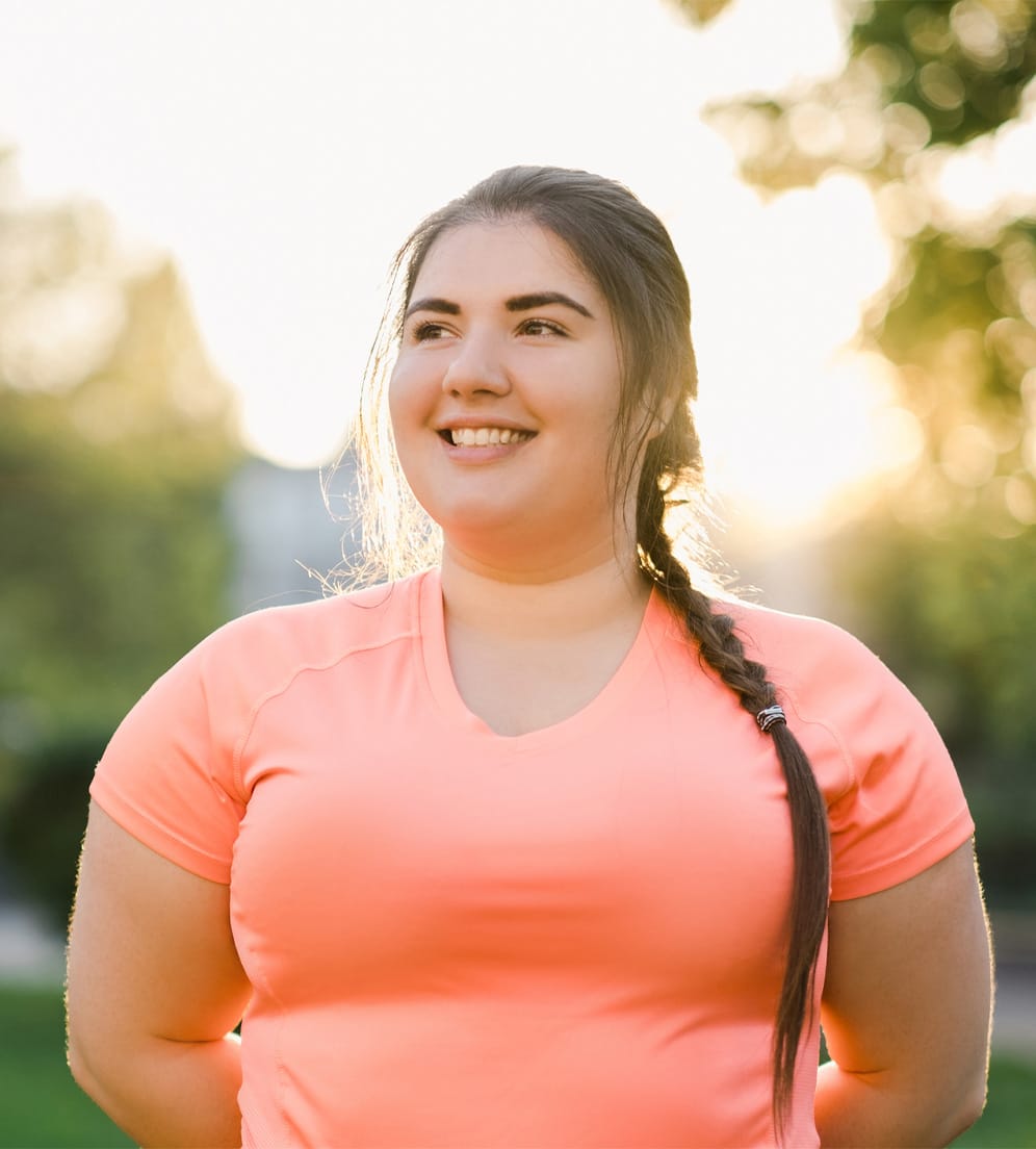 Teenage girl smiling and standing with arms behind her back
